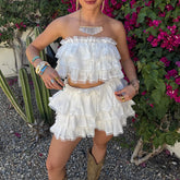Person wearing a white ruffled outfit with floral and cactus background
